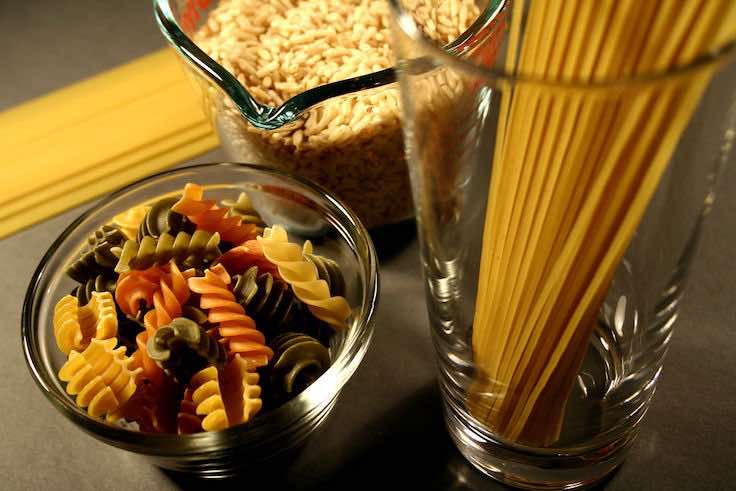 Carbohydrate rich foods including a drinking glass containing spaghetti